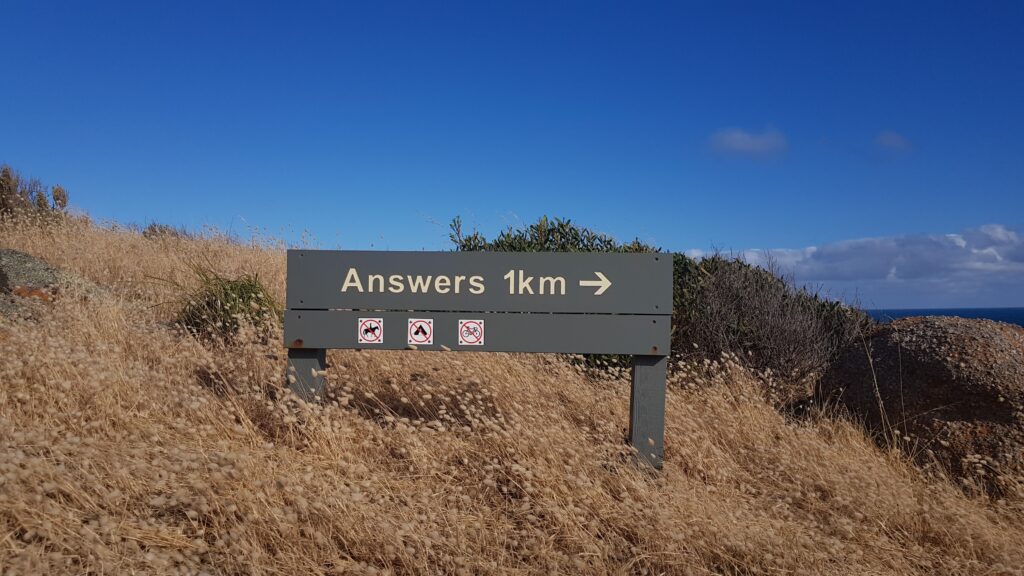 Signpost on a hill with 'Answers 1KM' and an arrow pointing to the right. Signifying all answers about Employee Engagement Signs are within this post.